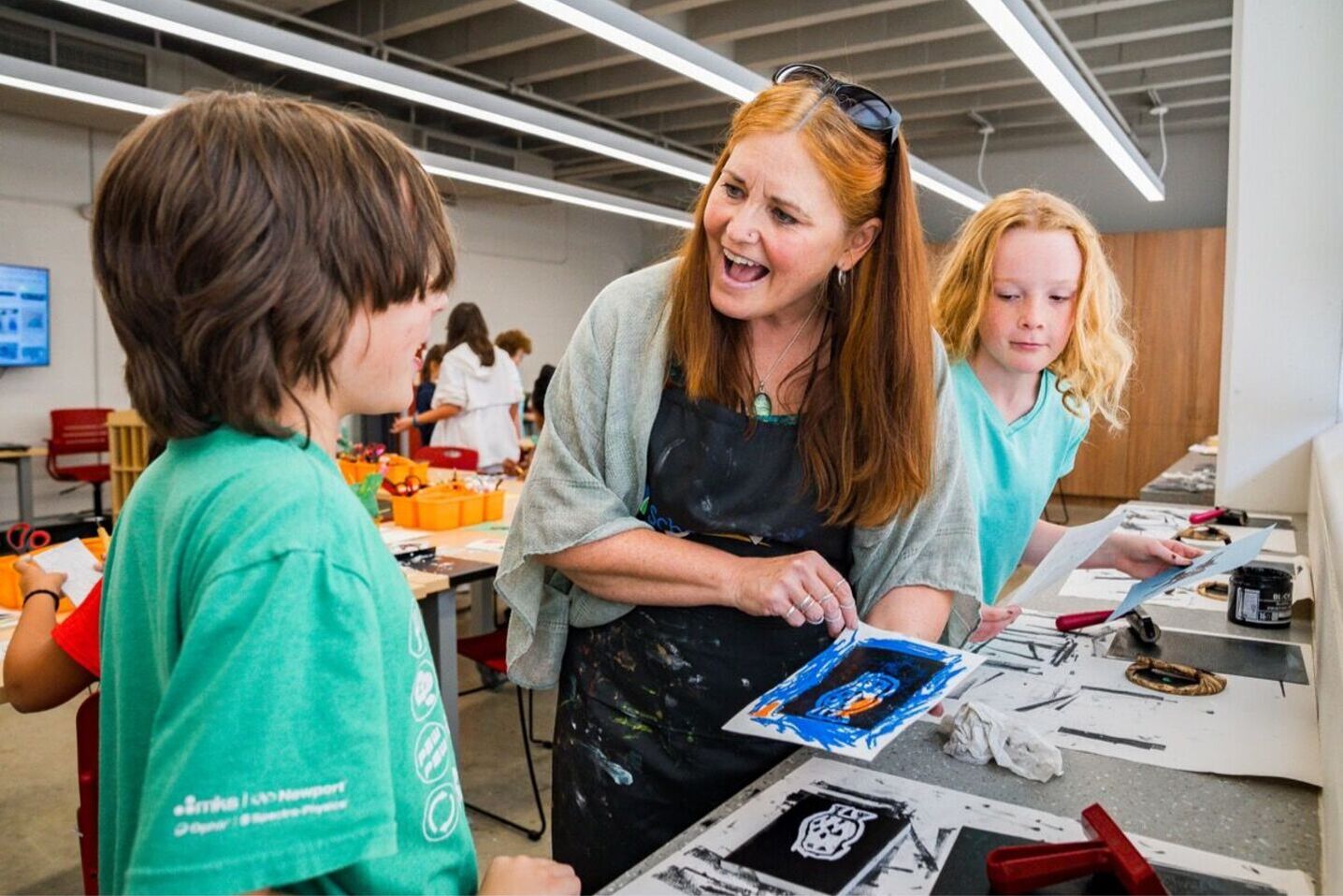 Red haired woman helping a kid with his art project