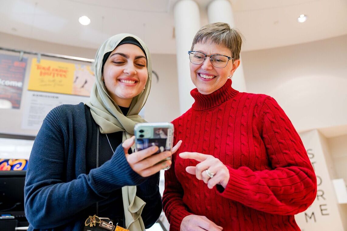 Two women smiling looking down at a phone